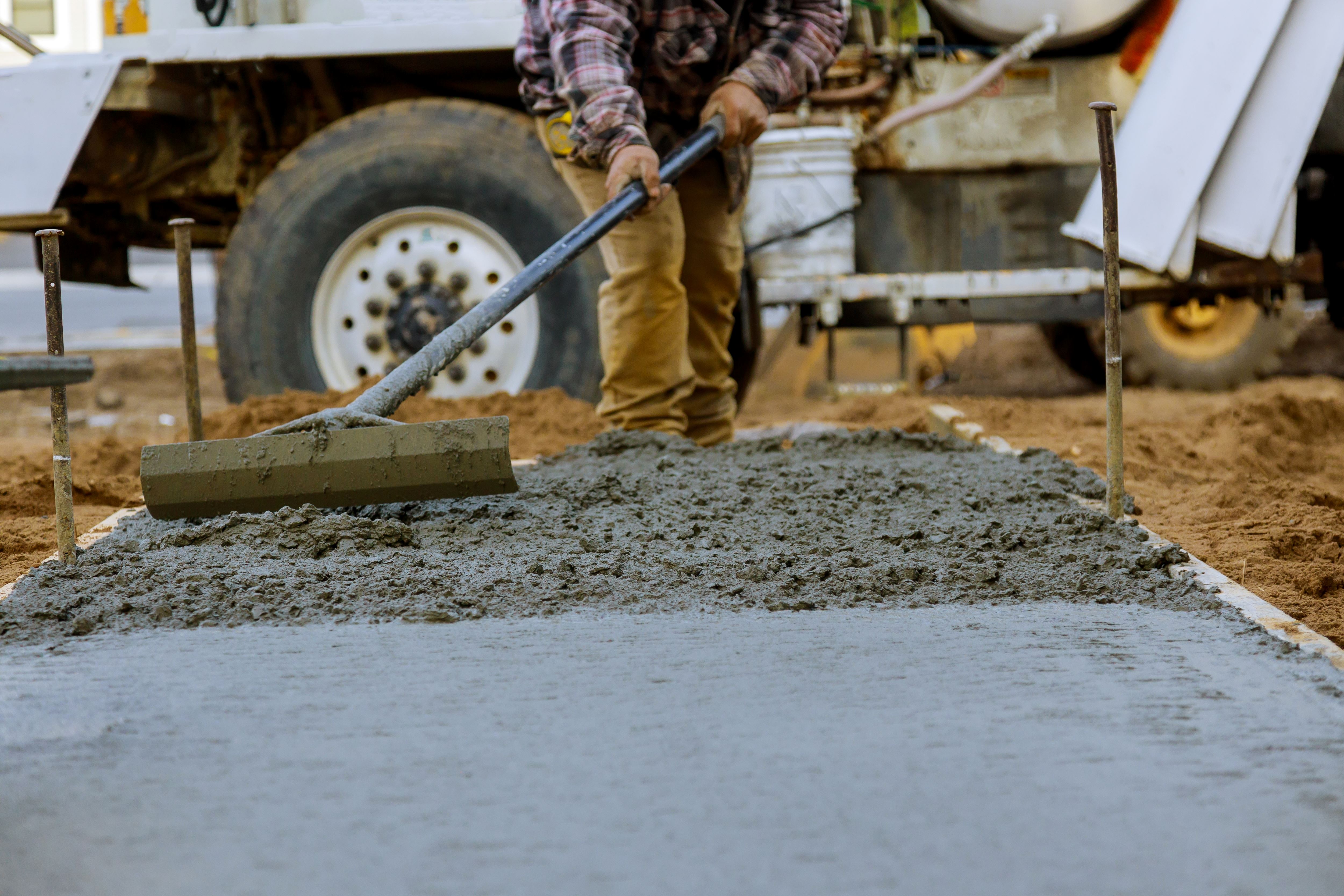 construction worker pours cement for sidewalk