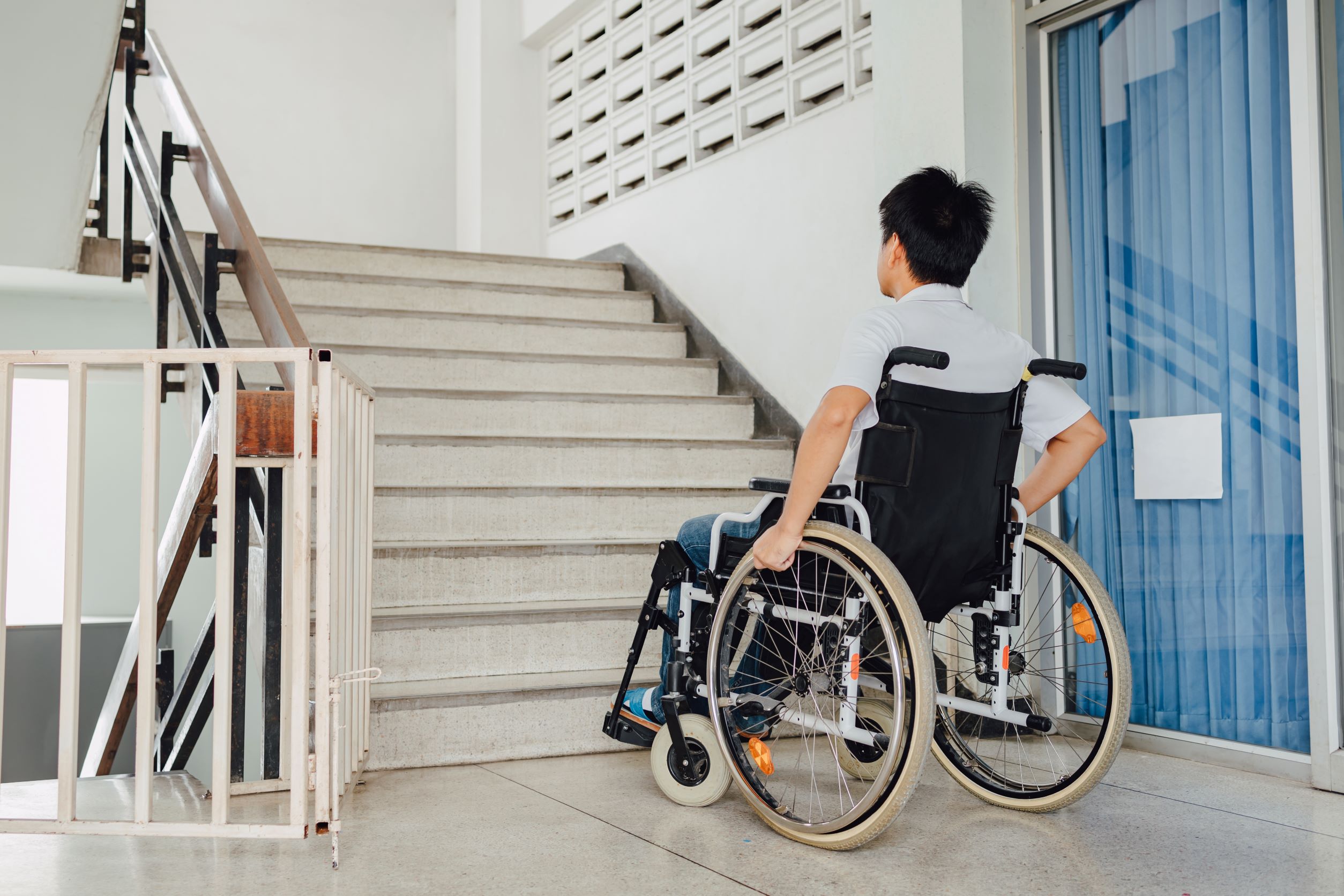 man in wheelchair in front of a staircase