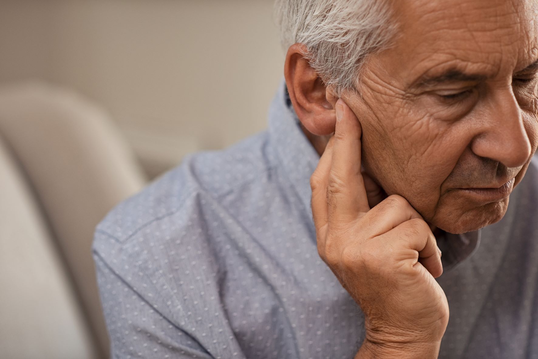 older man with hand to ear having trouble hearing